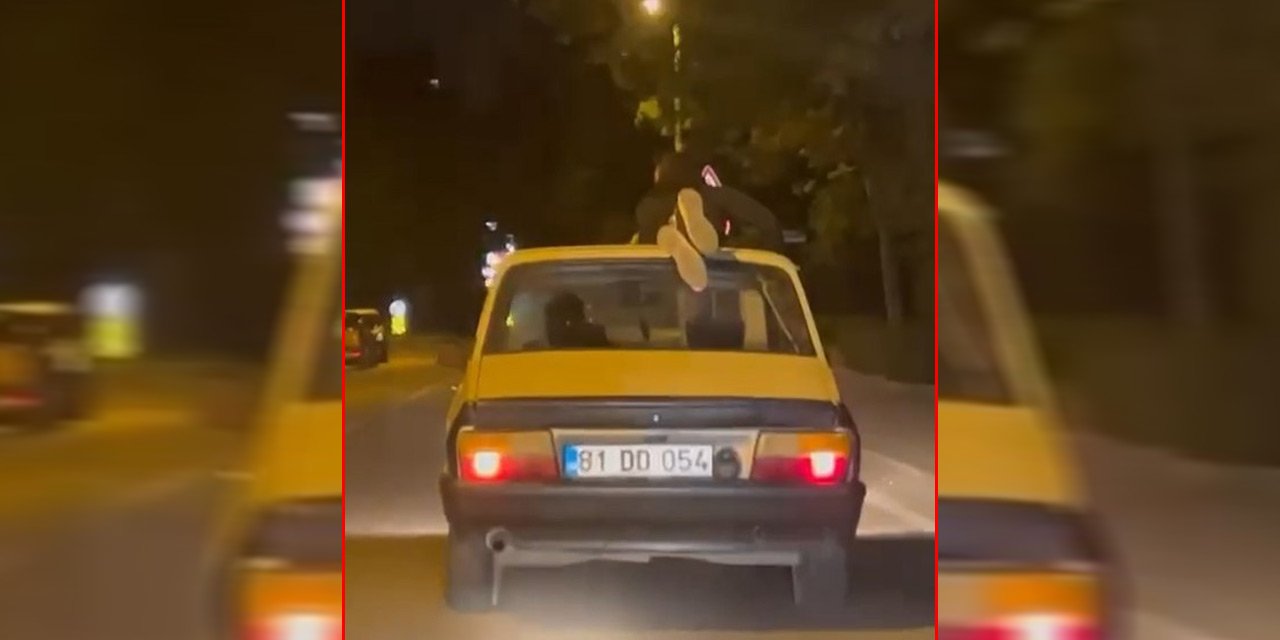 Trafikte tehlikeli anlar! Otomobilin tavanına uzanarak yolculuk yaptı